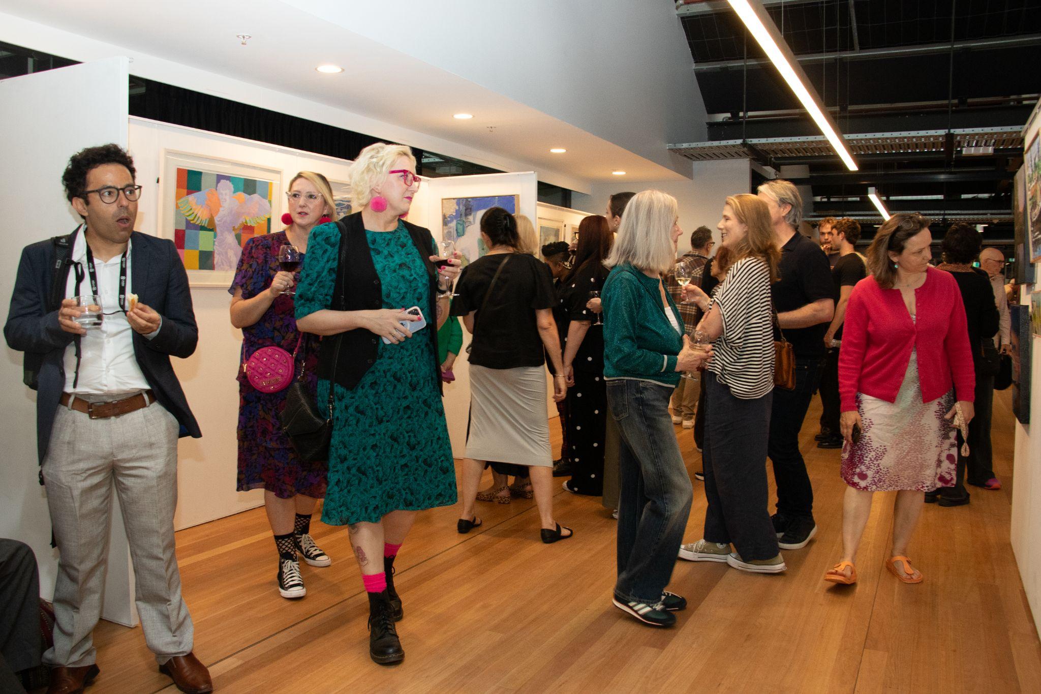 Guests walking around the gallery on opening night, discussing and perusing the artworks. Photograph: Orlando Sagar